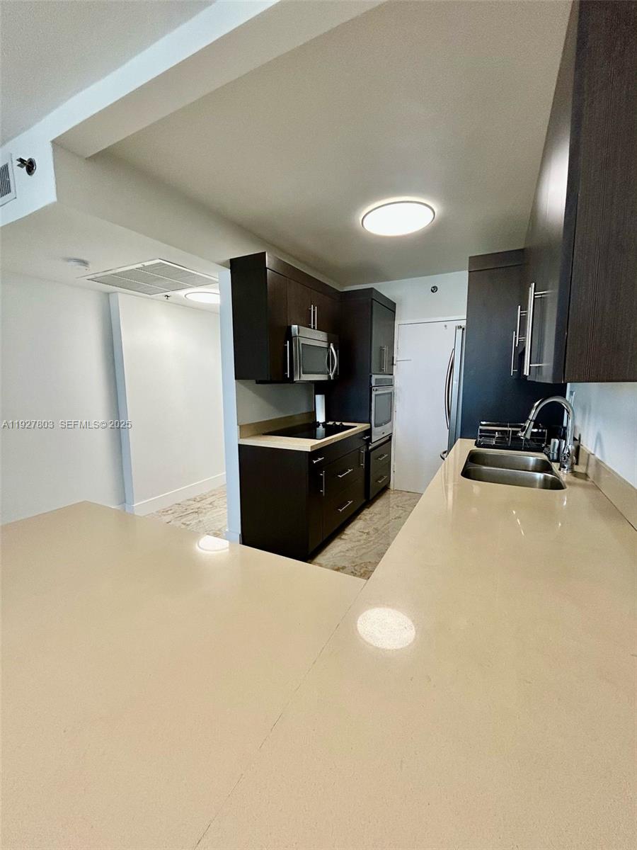 100 Lincoln Road, Unit 722 Miami Beach, FL 33139 - Photo 4 of 17 a kitchen with kitchen island a sink stainless steel appliances and cabinets