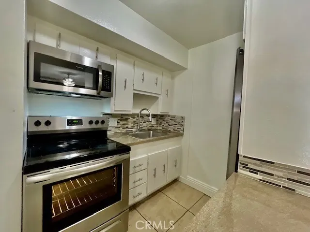 a kitchen with stainless steel appliances a stove a microwave and white cabinets