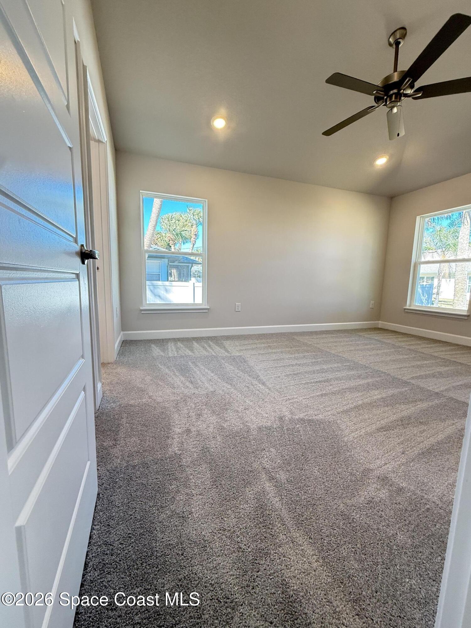 an empty room with windows and fan