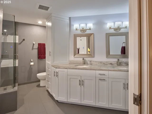 a bathroom with a granite countertop sink a toilet and a large mirror
