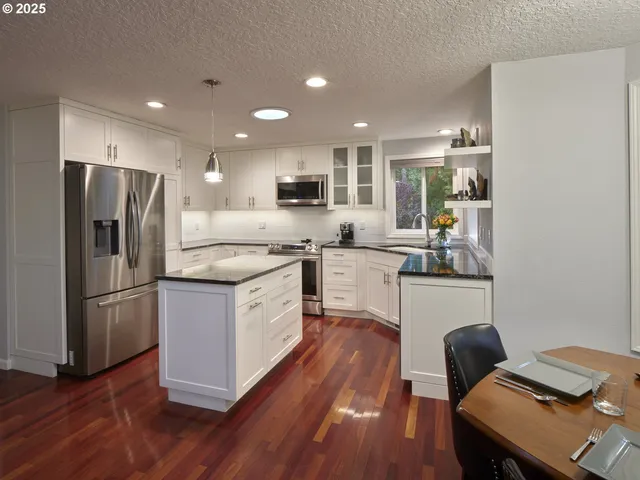 a kitchen with kitchen island a refrigerator a stove a sink a dining table and chairs