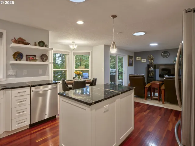 a kitchen with stainless steel appliances granite countertop a sink a stove and wooden floors