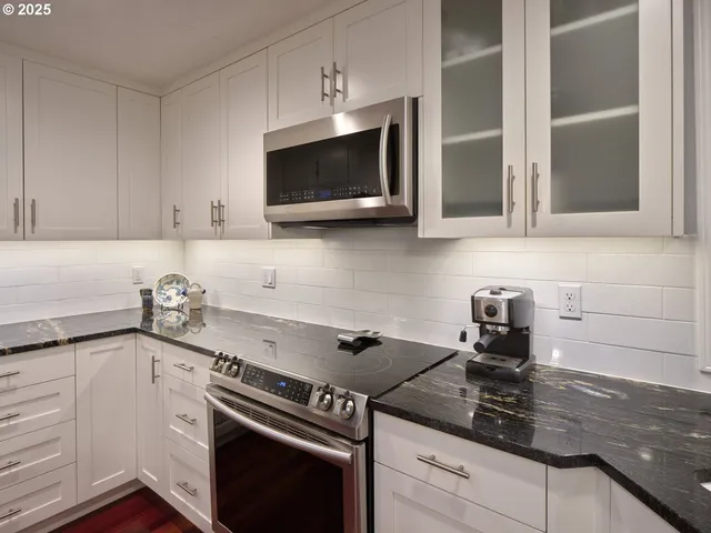 a kitchen with stainless steel appliances granite countertop white cabinets and a stove a oven with white countertops