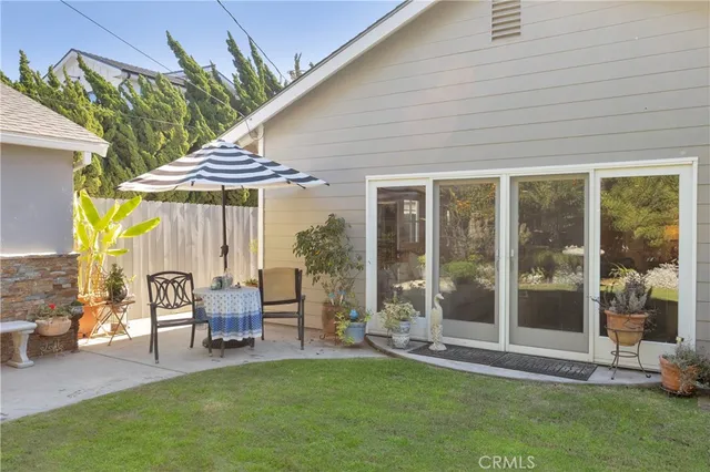 a patio with table and chairs and potted plants