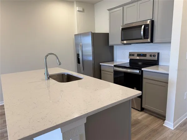 a kitchen with stainless steel appliances a refrigerator sink and microwave