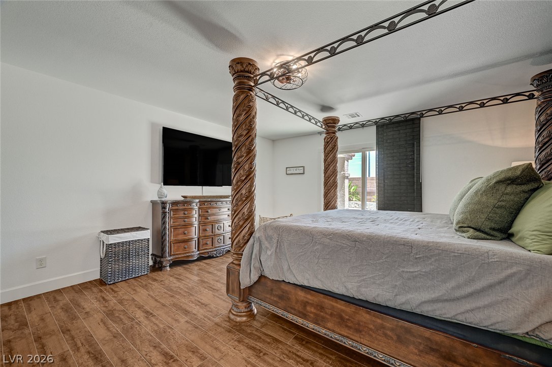 1072 Reed Point Court Henderson, NV 89002 - Photo 29 of 60 Ornate four-poster bed and wood-look flooring enhance this primary bedroom's inviting atmosphere.
