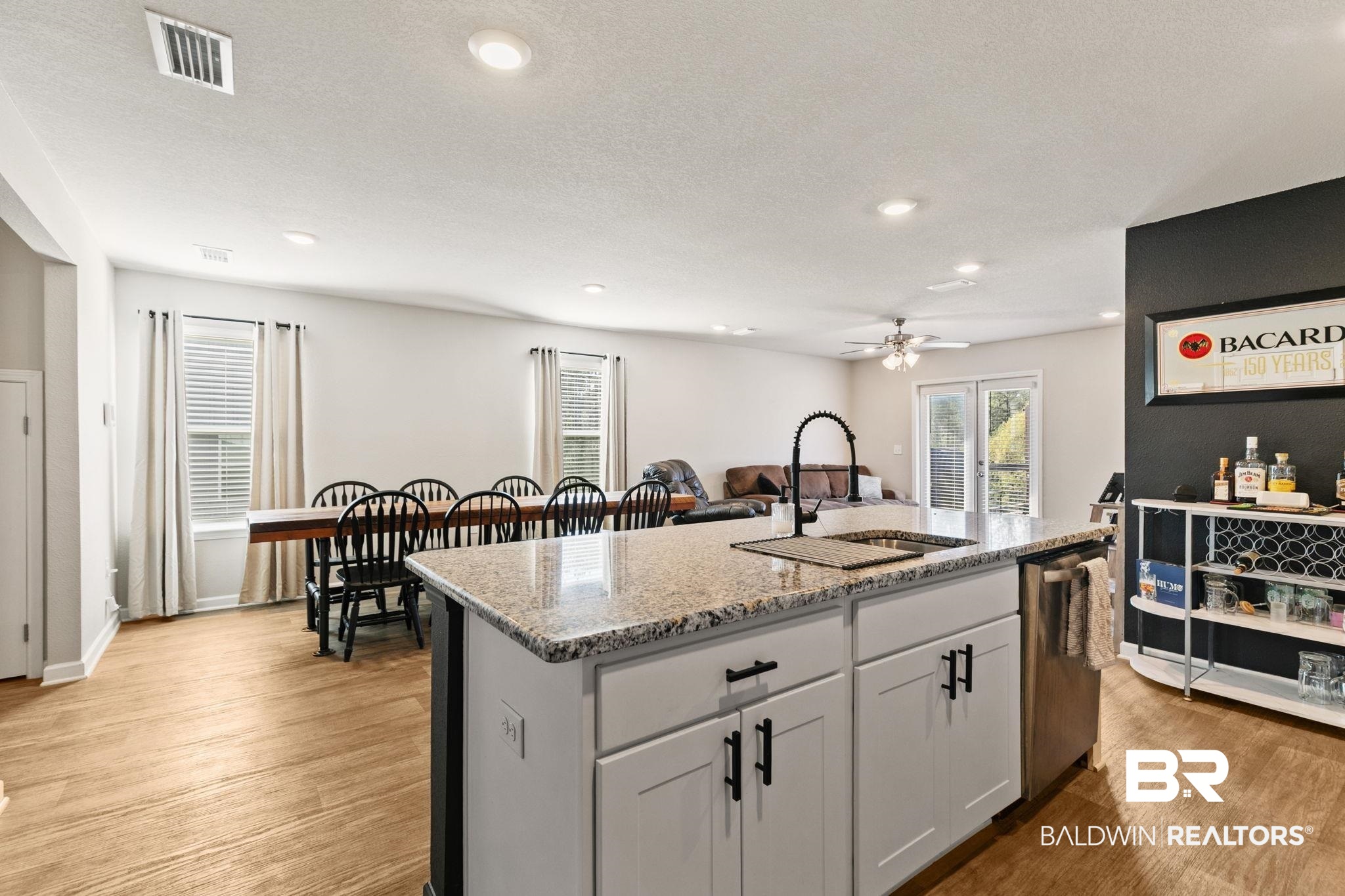 32234 Calder Court Daphne, AL 36527 - Photo 11 of 32 Kitchen featuring a center island with sink, light stone countertops, light wood finished floors, white cabinets, and dishwasher