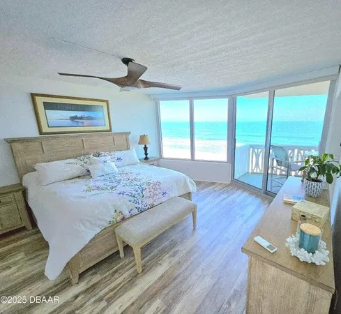 a bedroom with a balcony a bed and a table with wooden floor