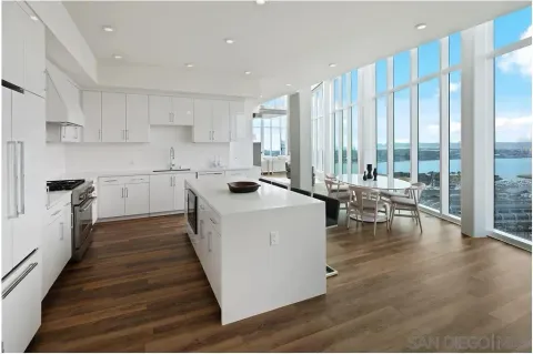 a large white kitchen with wooden floor and a sink