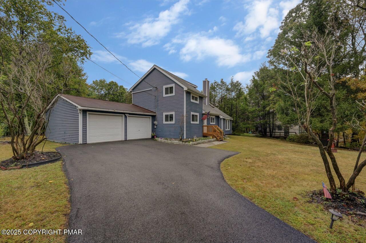 a view of a house with a yard garage and tree