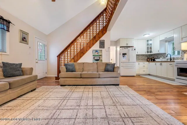 a living room with stainless steel appliances furniture and a kitchen view