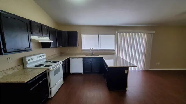 a kitchen with stainless steel appliances granite countertop a stove a sink dishwasher and a microwave oven with wooden floor