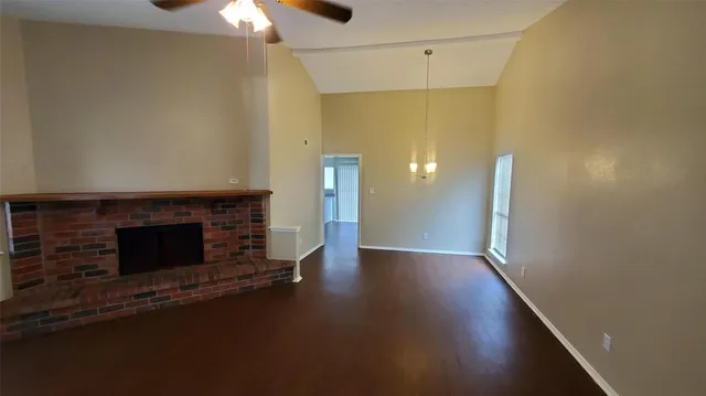 an empty room with wooden floor fireplace and windows
