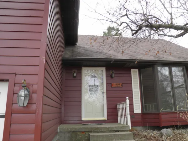 a front view of a house with a tree