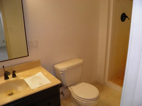 a bathroom with a granite countertop bathtub shower sink vanity and toilet