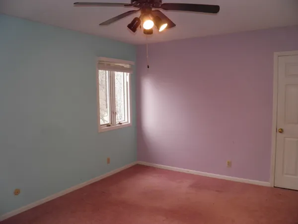 an empty room with a window and a fan
