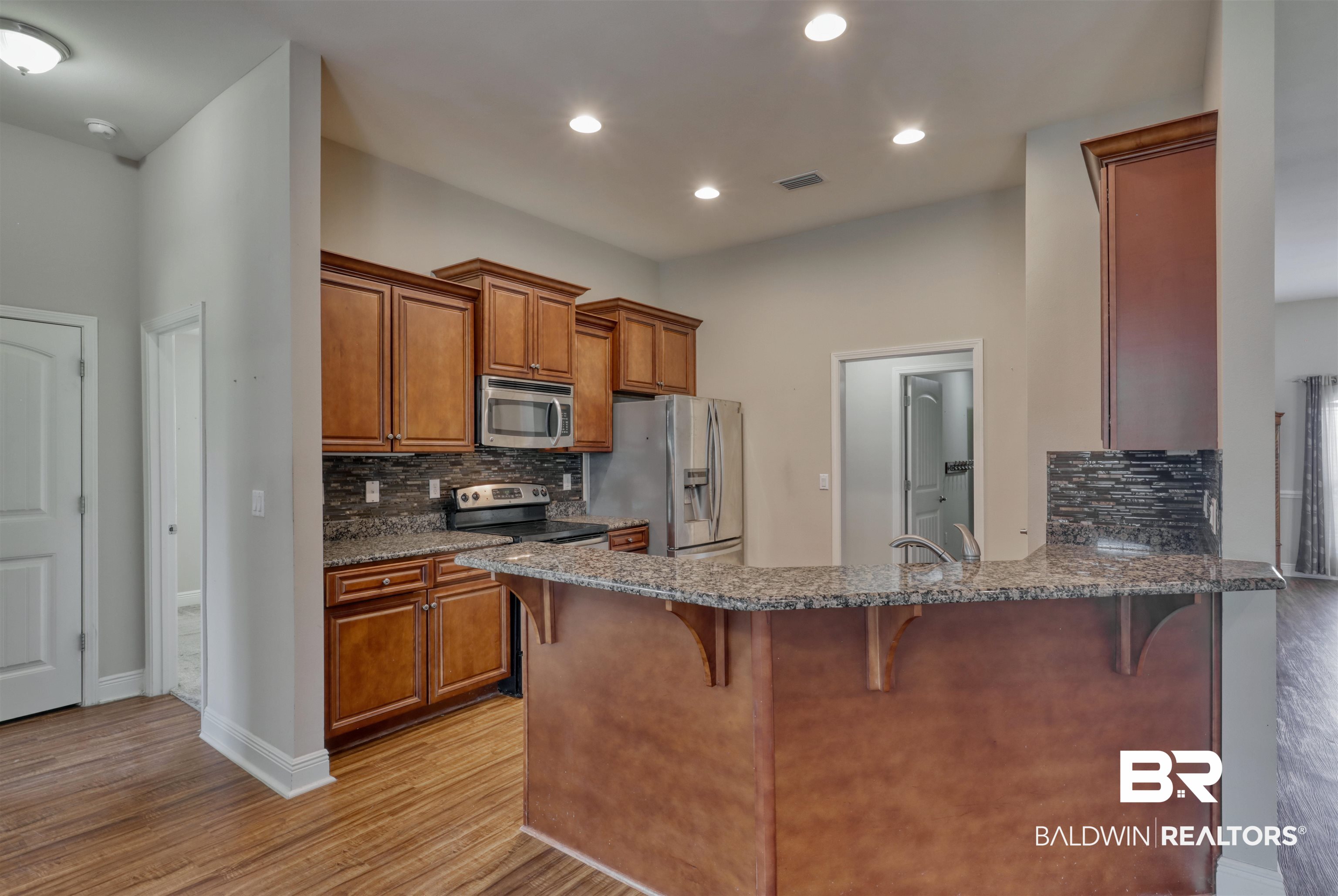 14794 Troon Drive Foley, AL 36535 - Photo 10 of 33 Kitchen featuring a kitchen bar, stainless steel appliances, brown cabinets, and visible vents