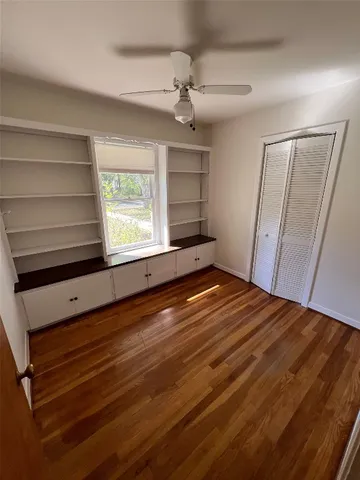 a view of empty room with wooden floor and fan