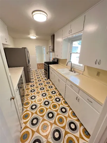 a kitchen with furniture a sink a window and stainless steel appliances