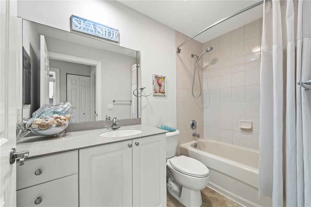 425 150th Avenue, Unit 2303 Madeira Beach, FL 33708 - Photo 47 of 69 a bathroom with a granite countertop sink a toilet a mirror and shower