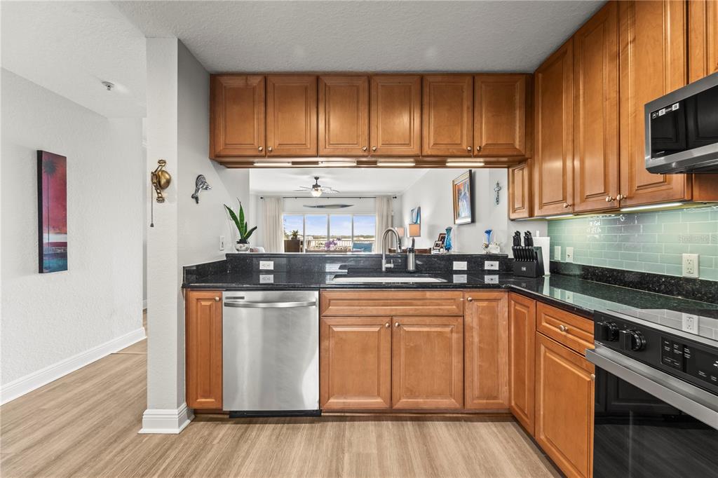 425 150th Avenue, Unit 2303 Madeira Beach, FL 33708 - Photo 10 of 69 a kitchen with stainless steel appliances granite countertop a stove a sink and a microwave