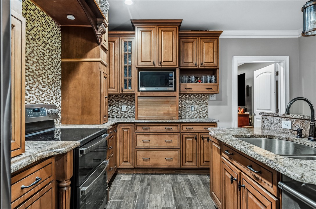 206 James Hare Road Anderson, SC 29626 - Photo 29 of 50 Well-appointed kitchen features rich wooden cabinetry, gleaming granite countertops, and a modern tile backsplash.