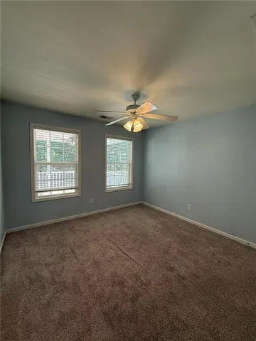 an empty room with windows and chandelier fan