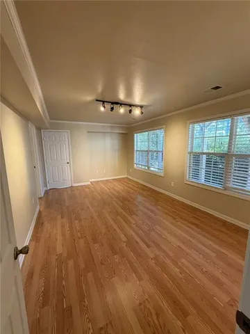 a view of empty room with wooden floor and fan