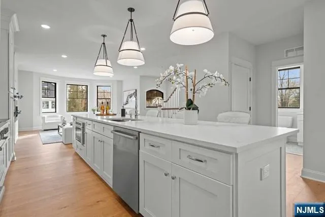 a large kitchen with kitchen island white cabinets and chandelier