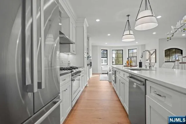 a large kitchen with stainless steel appliances a sink and cabinets