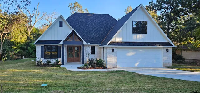 a front view of a house with a yard potted plants and a tree