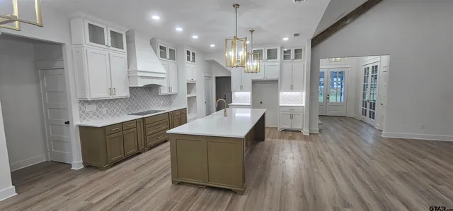 a kitchen with stainless steel appliances granite countertop a refrigerator a sink dishwasher a oven and a dining table with wooden floor