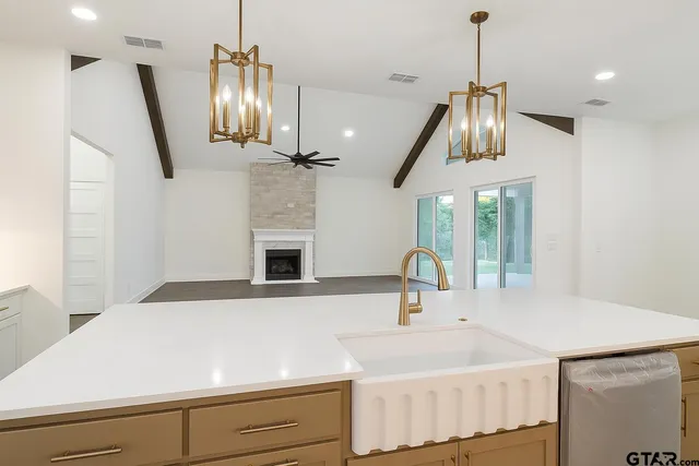 a kitchen with a sink chandelier and living room view