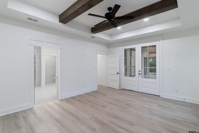 an empty room with wooden floor ceiling fan and windows