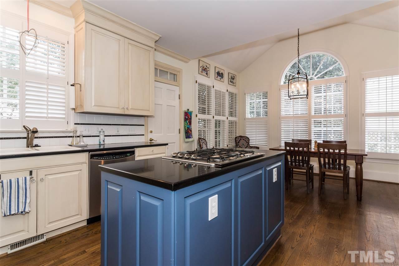 1712 Craig Street Raleigh, NC 27608 - Photo 8 of 25 a kitchen with stainless steel appliances granite countertop a stove a sink dishwasher a dining table and chairs with wooden floor