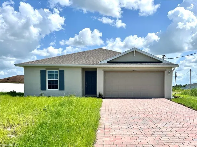 a front view of house with yard and trees in the background