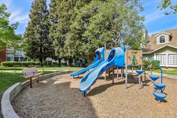 a view of a white house next to a yard with big trees