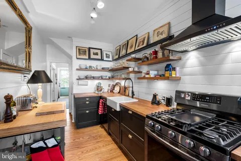 a room with stainless steel appliances a sink dishwasher a stove and a refrigerator with wooden floor