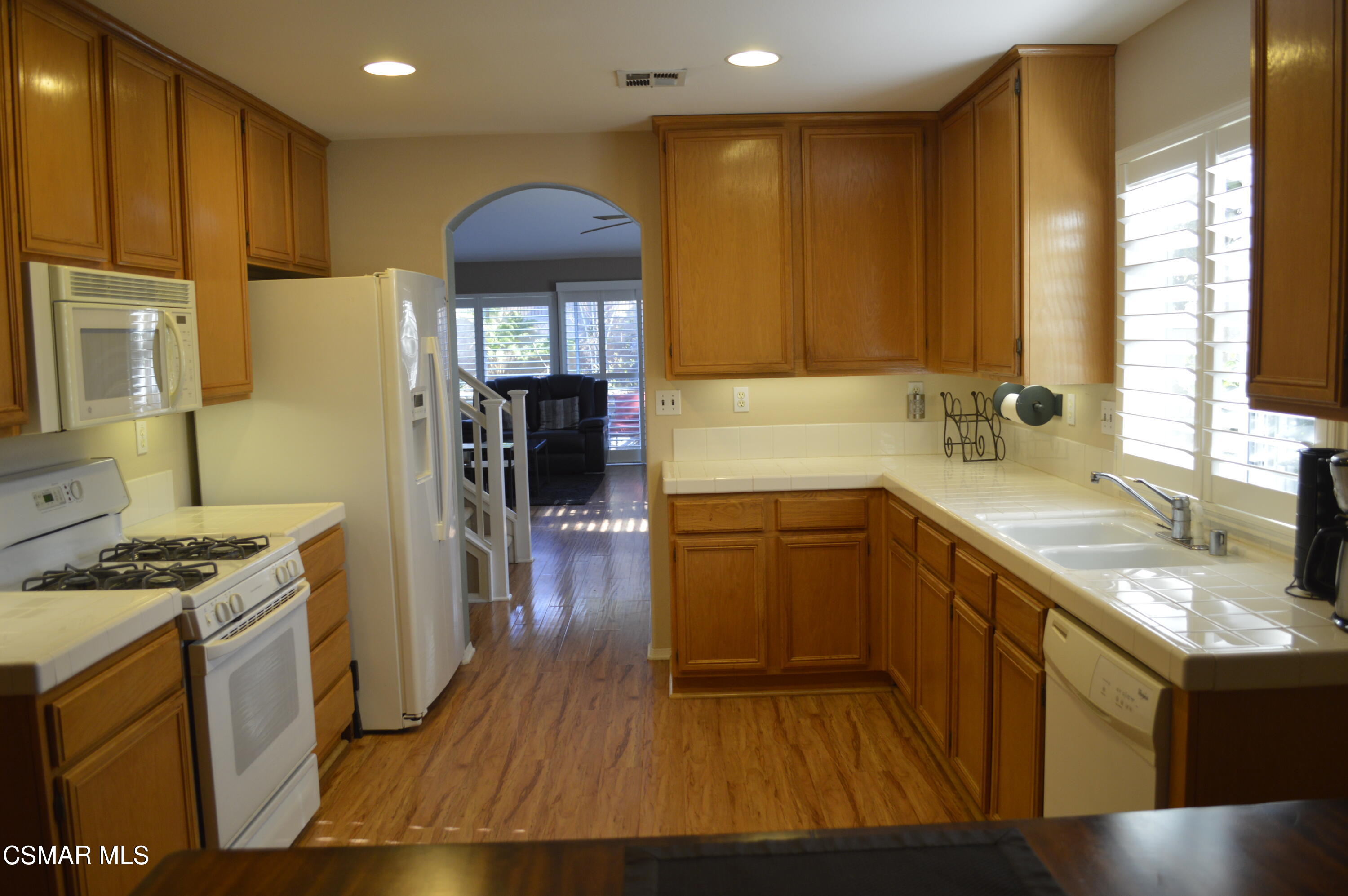 2040 Freesia Avenue Simi Valley, CA 93063 - Photo 8 of 23 a kitchen with granite countertop a stove a sink a refrigerator and wooden cabinets