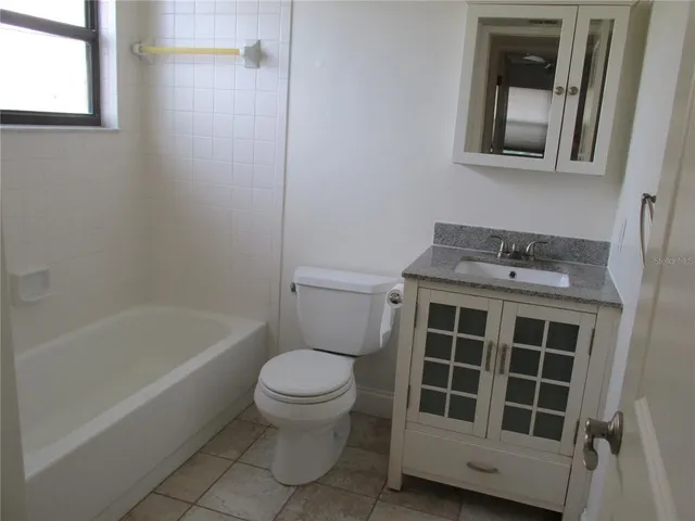 a bathroom with a granite countertop toilet a sink and bathtub