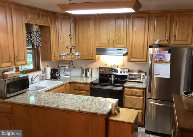 a kitchen with granite countertop a refrigerator stove and sink