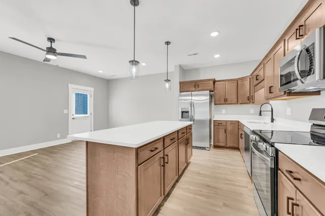 a kitchen with stainless steel appliances granite countertop a kitchen island a stove a sink and a refrigerator