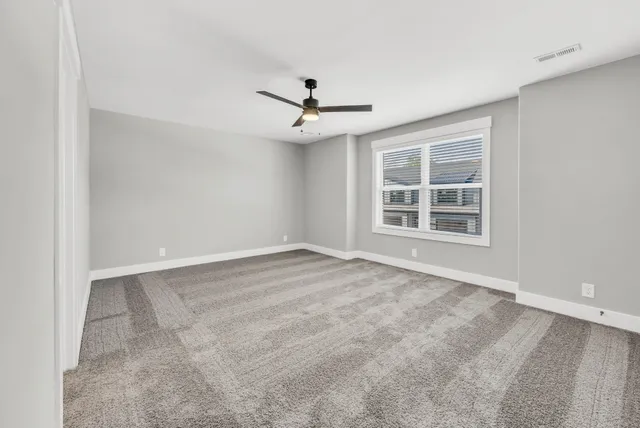 an empty room with windows and fan