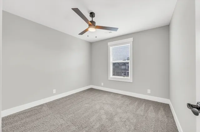 an empty room with a window and ceiling fan