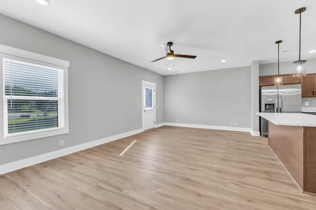 a view of an empty room with window and wooden floor