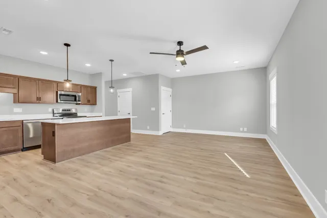 a large kitchen with stainless steel appliances kitchen island a large counter top and wooden floors