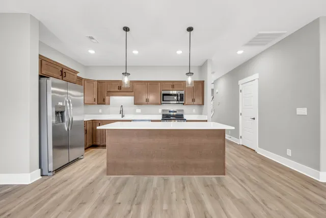 a large kitchen with stainless steel appliances granite countertop a stove a refrigerator a sink dishwasher and a oven with wooden floor