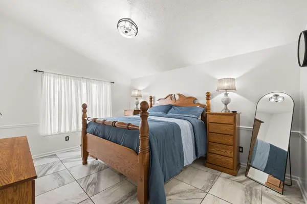 a bedroom with a bed and a mirror on dresser
