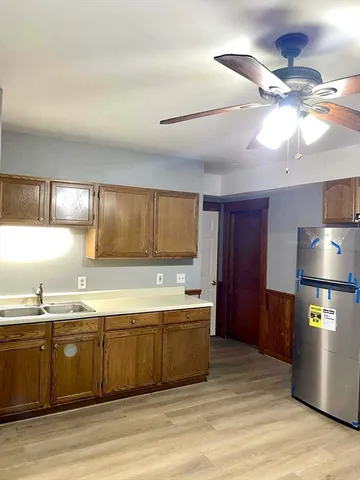 a large kitchen with stainless steel appliances a large counter top a sink and a refrigerator