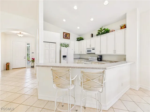 a view of kitchen with stainless steel appliances granite countertop white cabinets and window